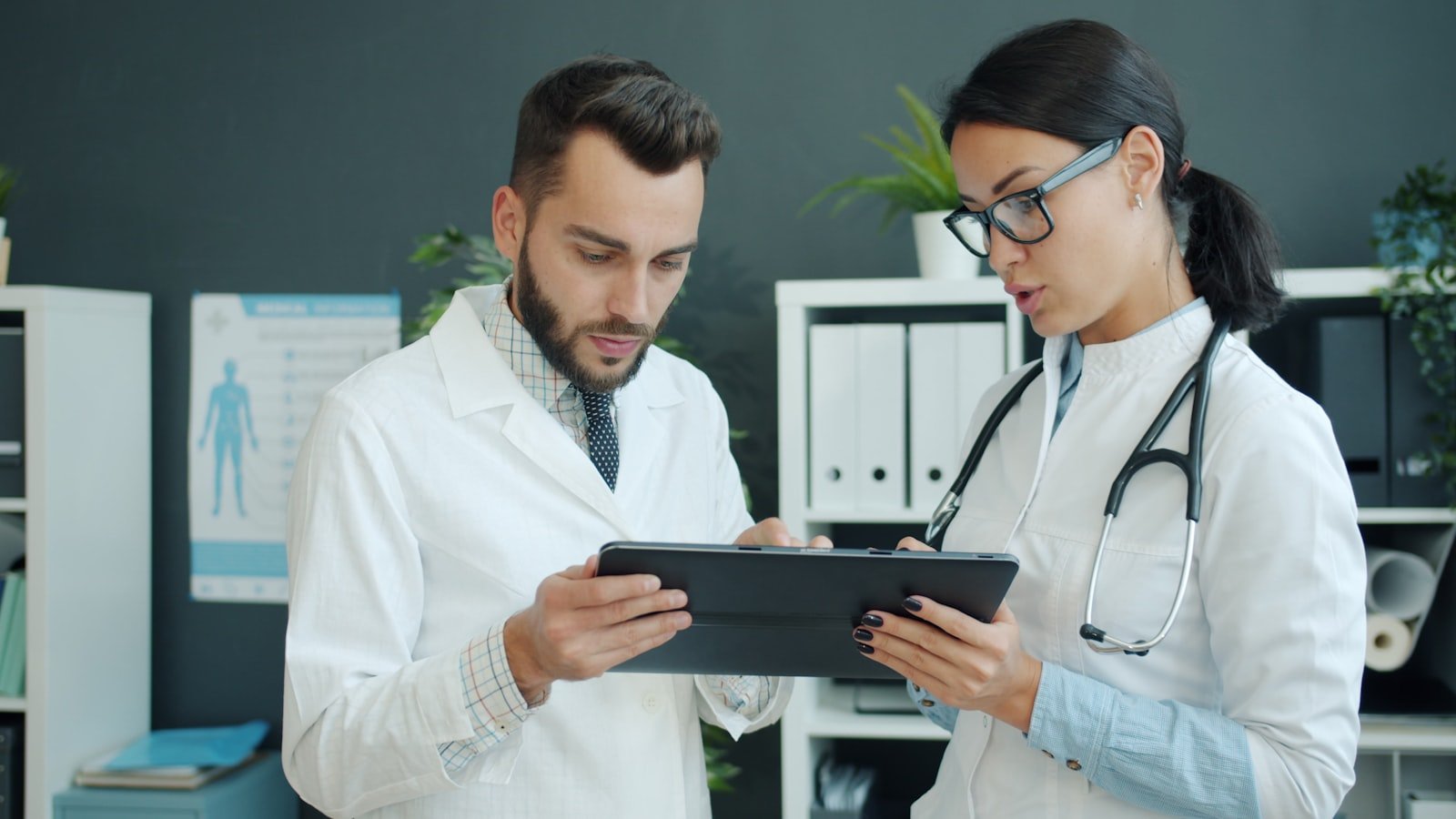 Two senior professionals reviewing clinical data on a tablet in a modern medical facility